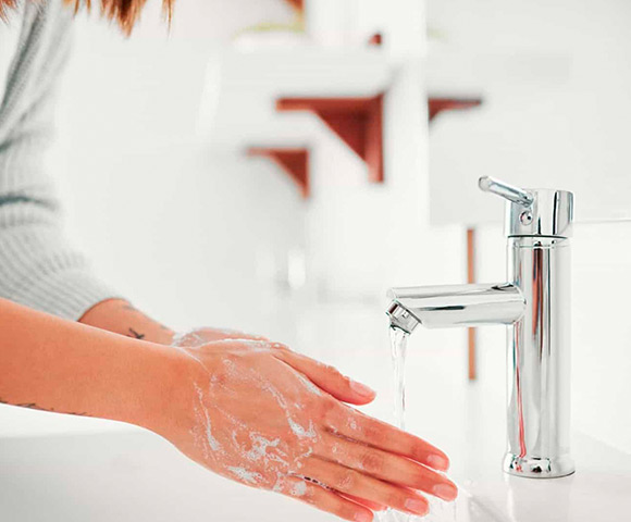 Mulher lavando as mãos na torneira da pia do banheiro