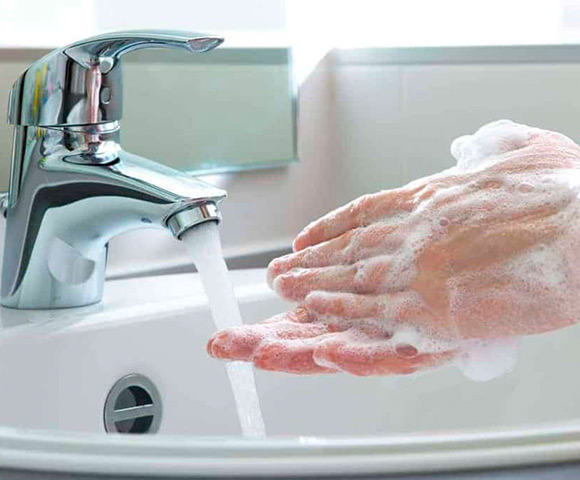 Mãos sendo lavadas na torneira da pia do banheiro