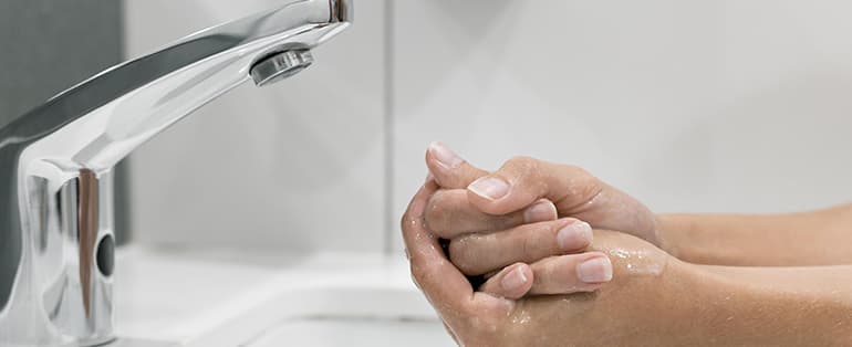 Mãos sendo lavadas em uma torneira com sensor